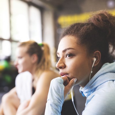 Young woman with earbuds having a break in gym