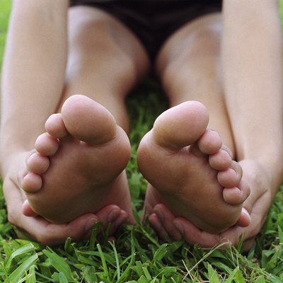 Young woman stretching, touching bottom of feet, close-up