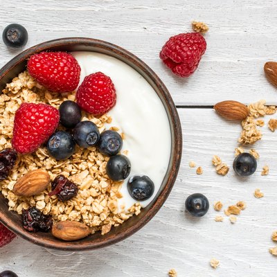bowl of oat granola with yogurt, fresh raspberries, blueberries and nuts