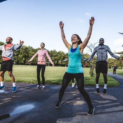 Group of friends doing jumping jacks exercise in a park