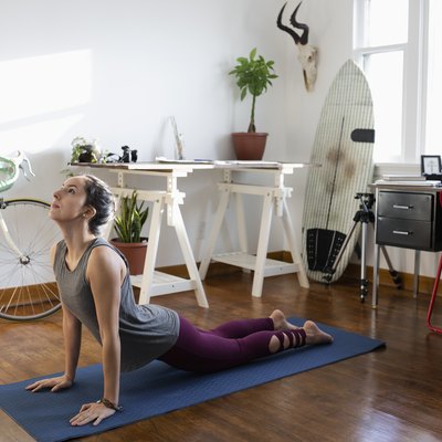 Young Latinx woman practicing yoga upward facing dog pose in apartment