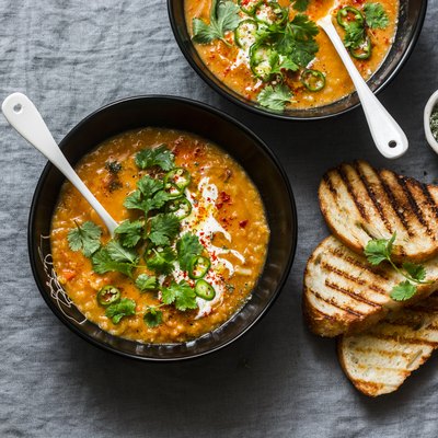 Curried red lentil tomato and coconut soup - delicious vegetarian food on grey background, top view. Flat lay served healthy lunch