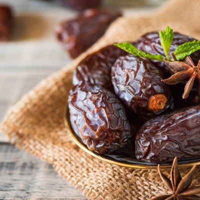 Ramadan food and drinks concept. Dates fruit and green Mint leaves in a bowl on wooden table background.
