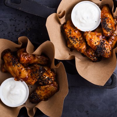 Glazed spicy chicken wings with sesame seeds served in cast iron skillets