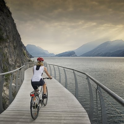 Female tour cyclist rides a modern cycle path around Lake Garda