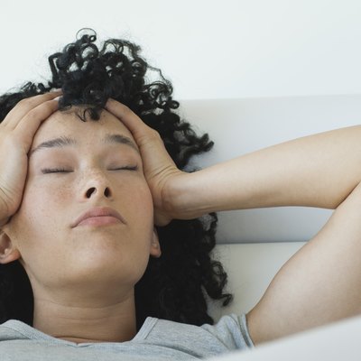 Young woman holding her head, eyes closed