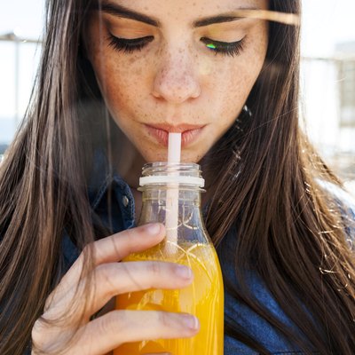 Young woman with freckles drinking orange juice