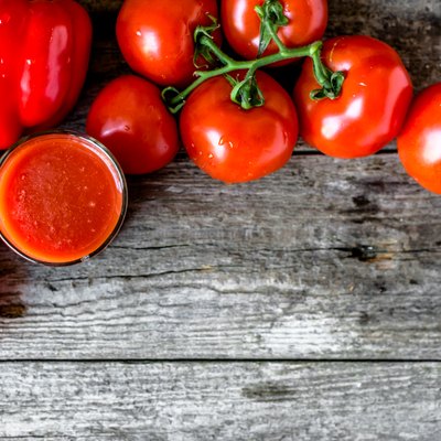 Glass of tomato juice on wooden table, flat lay from above