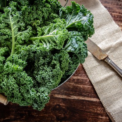 Kale in basket and knife on wooden background top view on daylight superfood vegetables