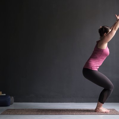 Woman practicing yoga, doing Chair exercise, Utkatasana pose, working out.