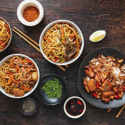Bowls with chicken, beef and vegetables chow mein and rice with pork