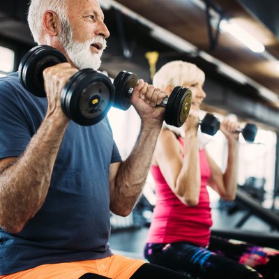 Fit senior man and woman doing exercises in the gym to combat belly fat and weight gain