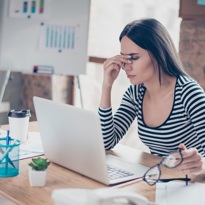 Overworked tired secretary holding spectacles and touching her nose bridge