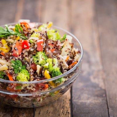 Quinoa and vegetable salad in a glass bowl on a wooden table