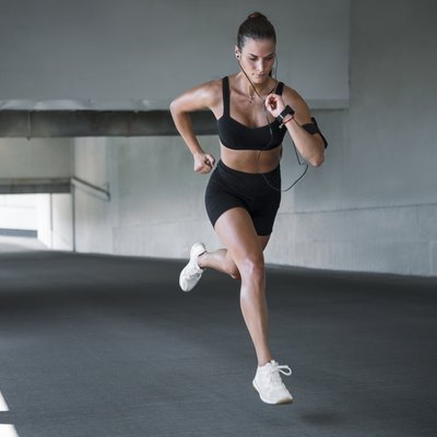 Young sportswoman running outdoors through concrete tunnel