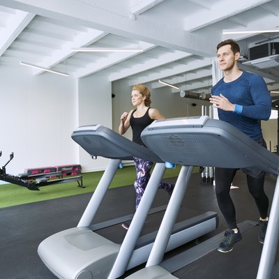 Man and woman running on treadmill at gym