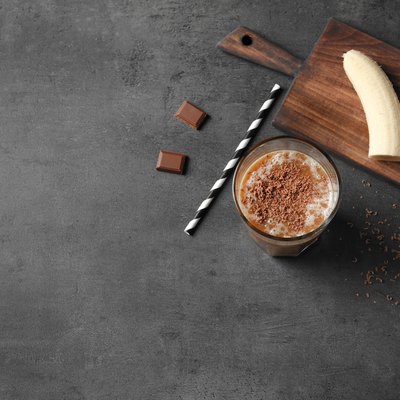 Glass with chocolate protein shake on table