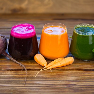 three vegetable juice in glass cup on wooden background