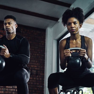 man and woman holding kettlebells doing muscle-building goblet squats