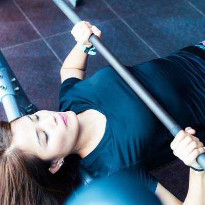 Asian girl lifting weights at the bench press