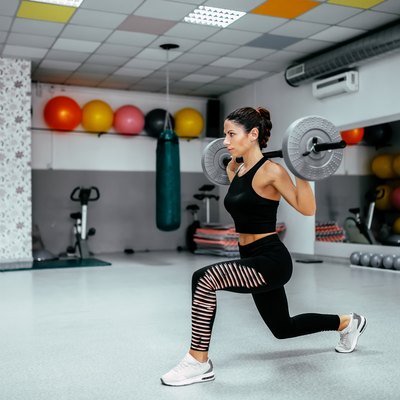 Side view portrait of a young woman doing weighted lunge.