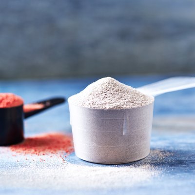 Scoop of Whey Protein and Creatine Powder. Sport nutrition. Rustic wooden background. Close up. Copy space