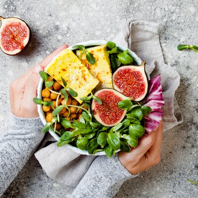 Vegan, detox Buddha bowl recipe with plant-based protein foods and turmeric roasted tofu, figs, chickpeas and greens. Top view, flat lay