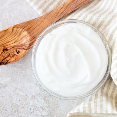 Greek yogurt, with cloth and spoon on white marble