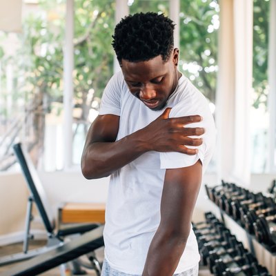 Sportsman holding shoulder that pops and cracks in gym