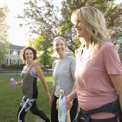 Smiling senior women walking, exercising in sunny park