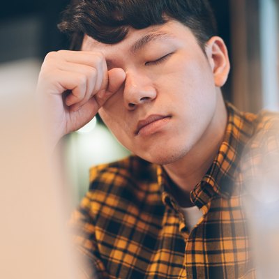 Exhausted young man rubbing eyes in cafe