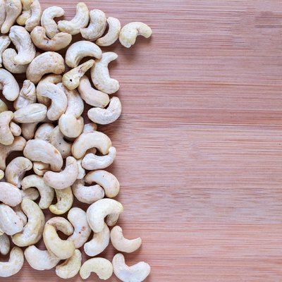Cashew pile on wooden background. Cashew photo wallpaper. Organic food rustic banner template with text space