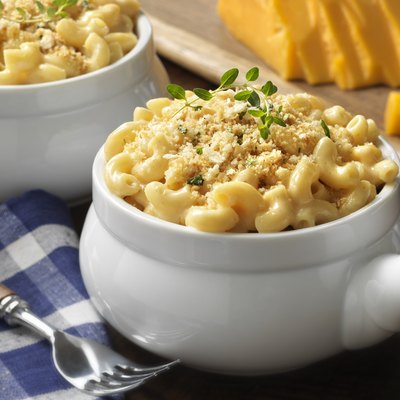 Macaroni and cheese in a white bowl on blue plaid tablecloth