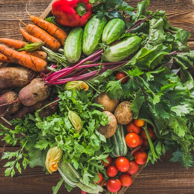 Fresh organic vegetables harvest. Local farmer market with vegetable box on wooden background, vegetarian food concept