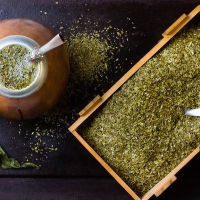 Yerba mate in calabash and wooden box of dry herb.