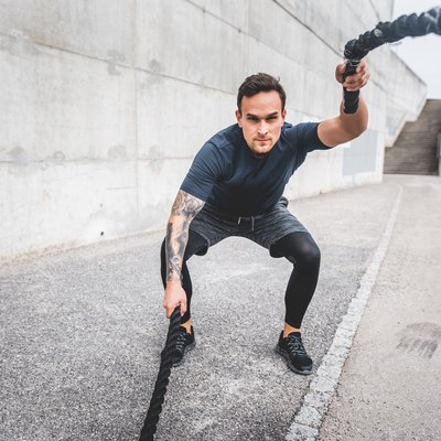 Focused Male Athlete Doing a Workout Finisher with Battle Ropes Outdoors