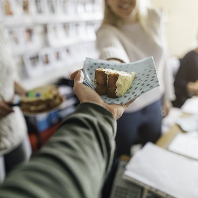 A woman accepting a slice of cake at an office birthday celebration