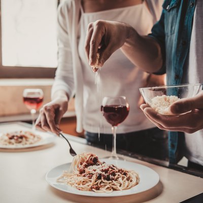 Young couple eating pasta and drinking alcohol, which are some of the foods to avoid with IBS