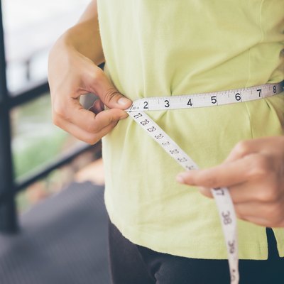 Midsection of Woman Measuring Her Waist With Tape Measure