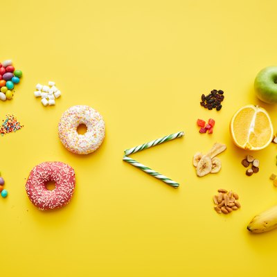 Choosing healthy sugar concept: sweets and baked food is less than fresh and dried fruits on bright yellow background