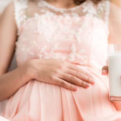 Midsection Of Pregnant Woman Holding Milk Glass