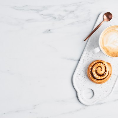 Freshly baked cinnamon roll and coffee with latte art
