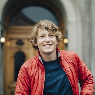 Portrait of smiling teenager against building in city