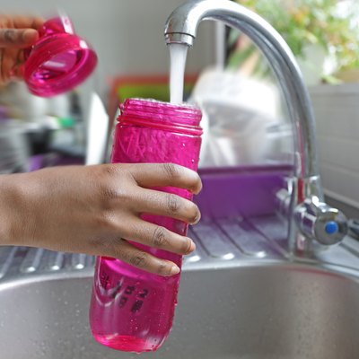 Detail of hands filling water bottle at a sink