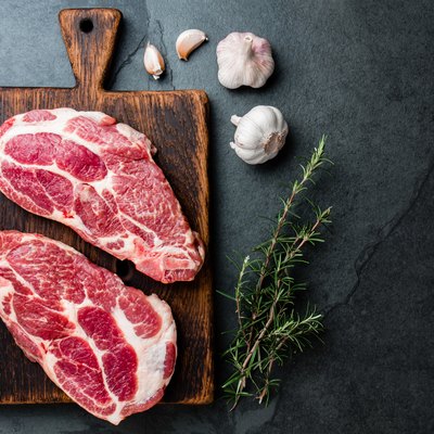 Raw pork cutlet chop for grill BBQ with herbs on wooden board, slate background, top view, copy spaces