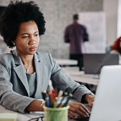 African American businesswoman typing an e-mail on laptop at work.