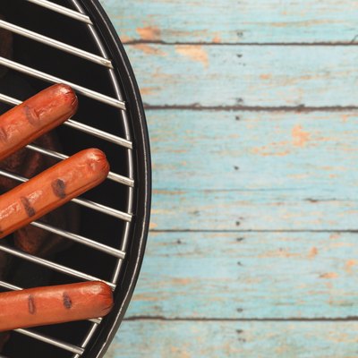 Three Hotdogs Grilling on Rustic Blue Picnic Table