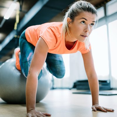 Young attractive woman doing push ups using ball