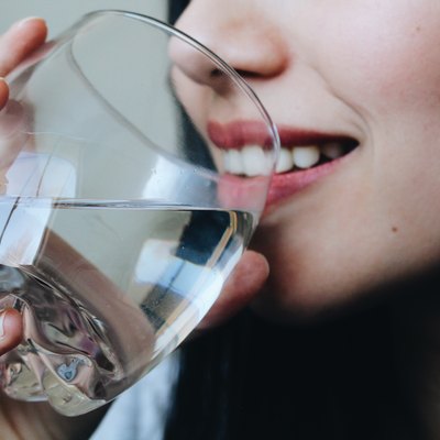 Close-Up Midsection Of Young Woman Drinking Water At Home