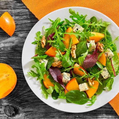 salad with persimmon slices, mix of lettuce leaves, blue cheese